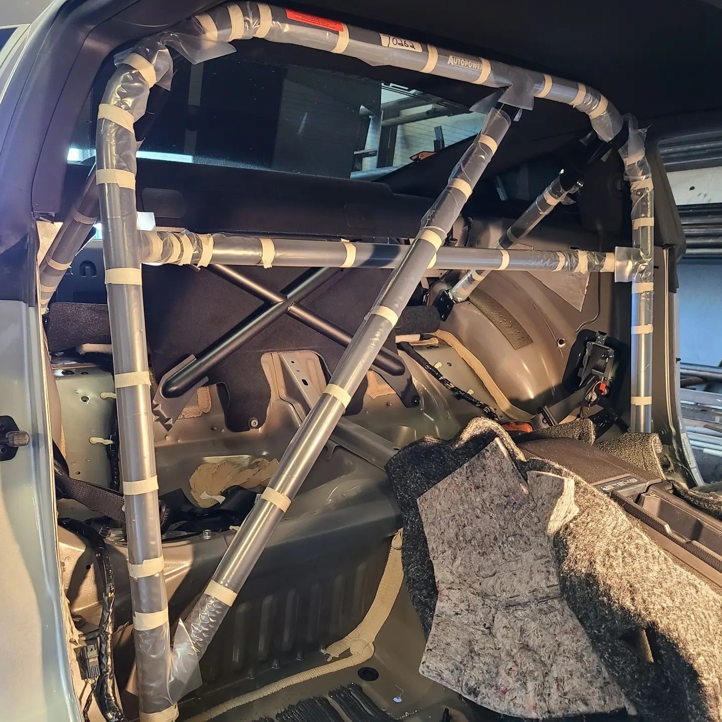 Interior of a car with a roll cage installed, taped together, gray metal and black.