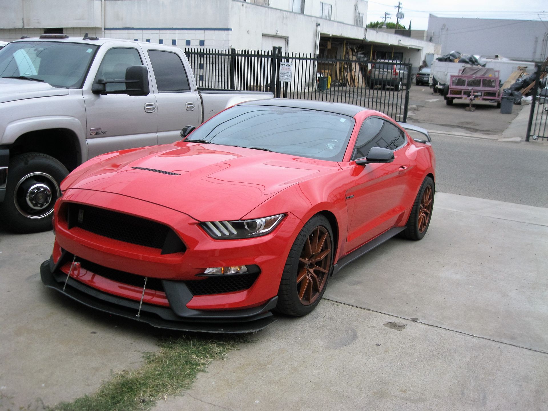 Red Ford Mustang sports car with black accents parked on pavement.