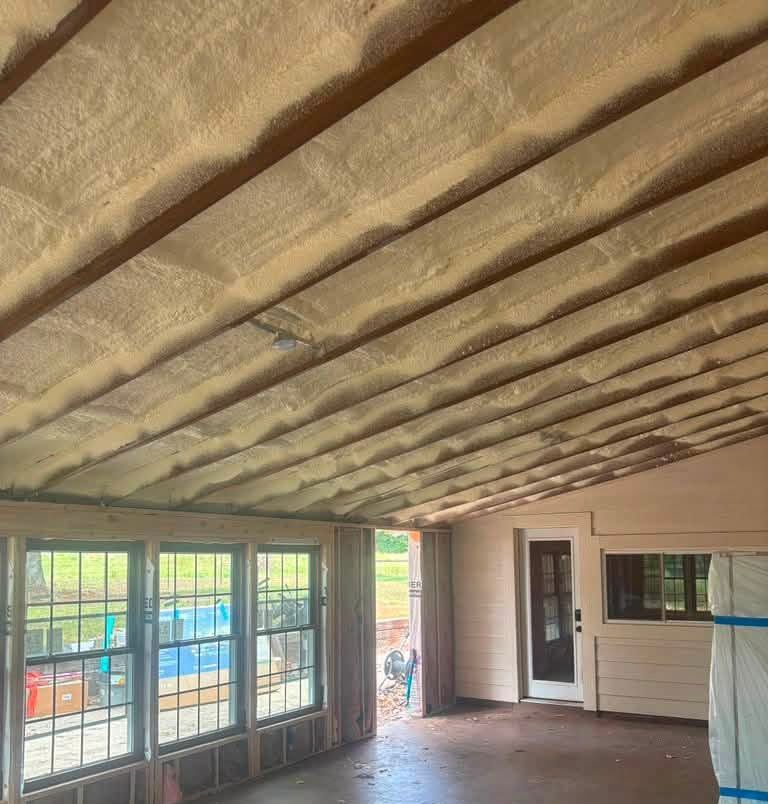 Partially finished room with exposed insulation, large windows, and a door opening to a deck.