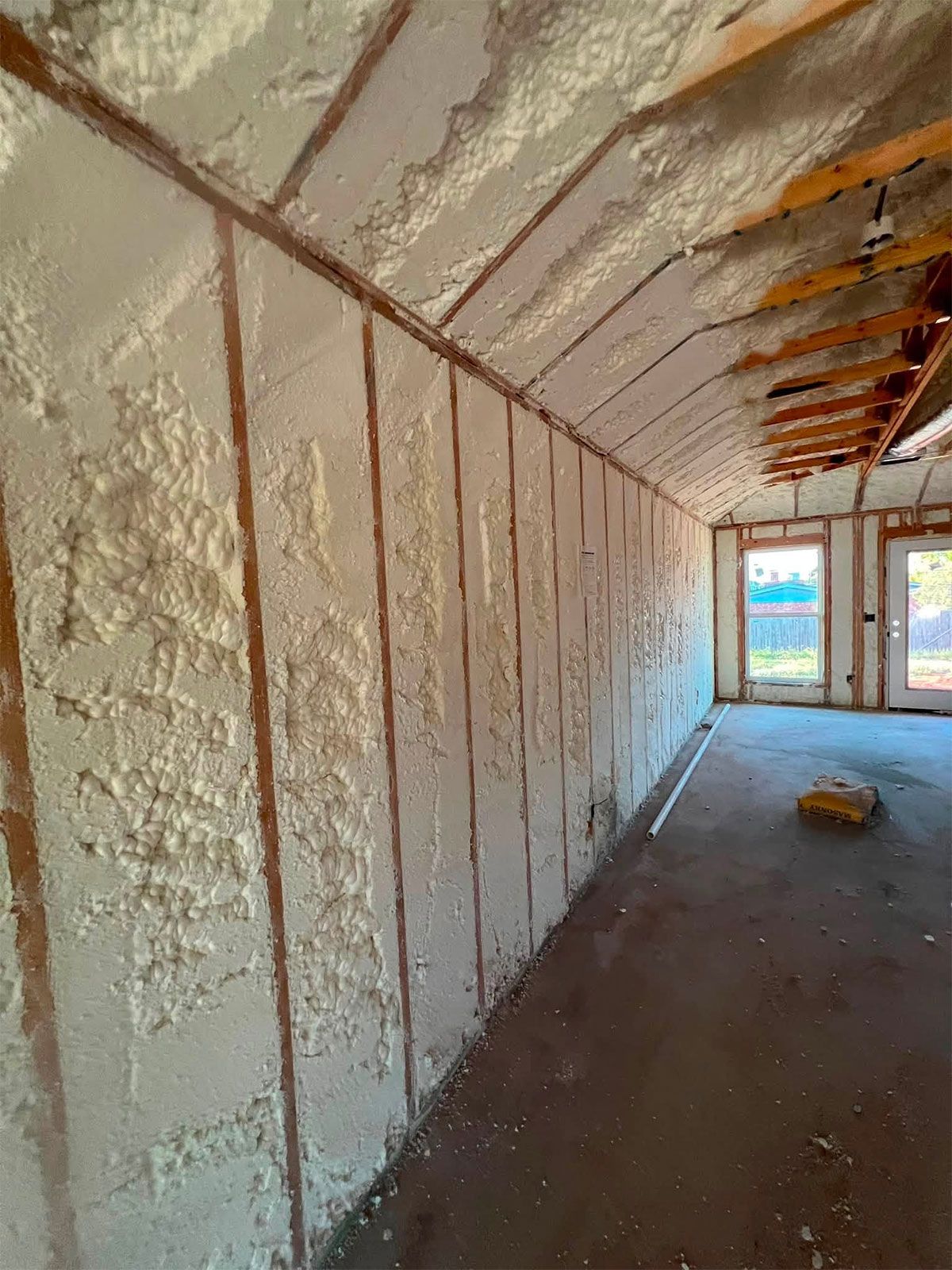 Unfinished insulated hallway with exposed framing and double doors at the end