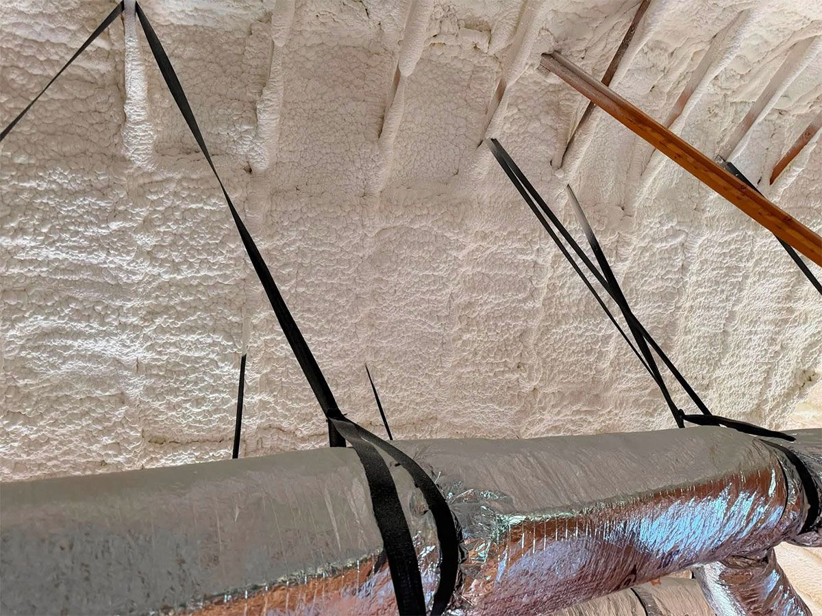 Close-up of a rusty pipe with black straps against a rough beige ceiling.