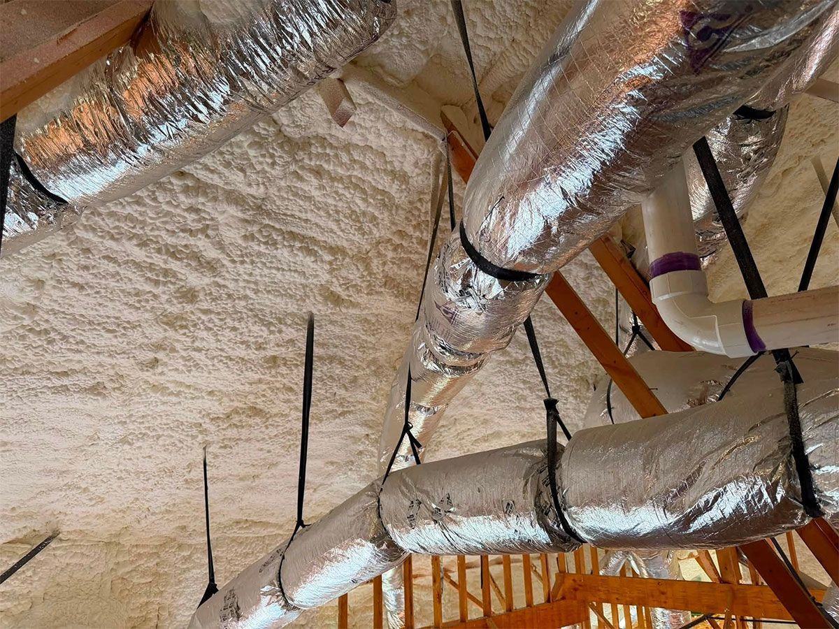 Foam-insulated ceiling with silver ventilation ducts and exposed wooden beams