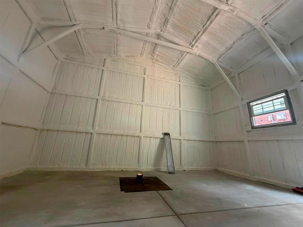 White vaulted interior with a small furnace in the center, ladder at back, and a window on the right.
