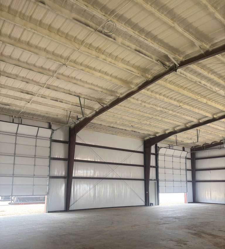 Empty industrial warehouse interior with high insulated ceiling, metal walls, and concrete floor