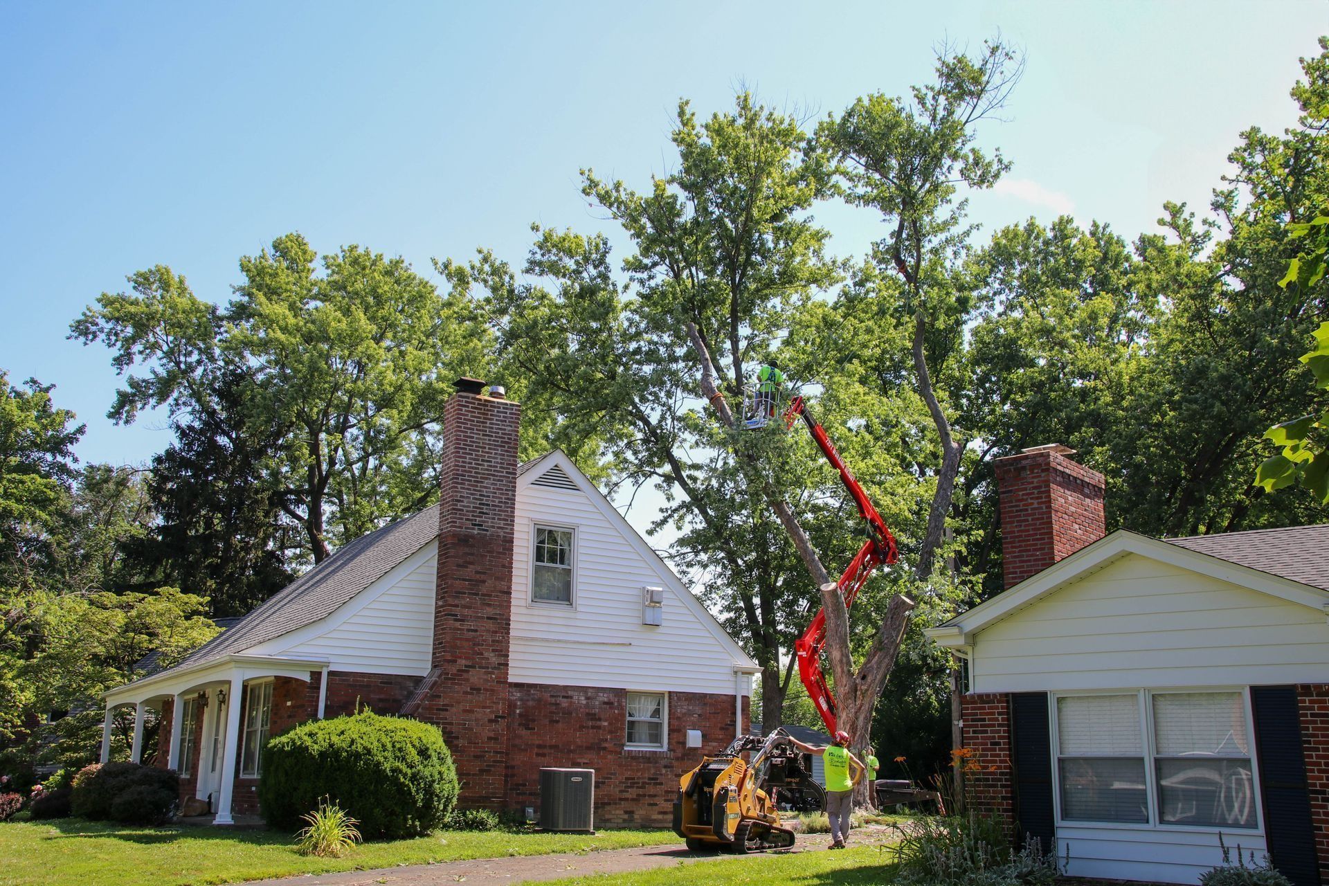 Tree removal in progress near two houses; cherry picker and worker visible.