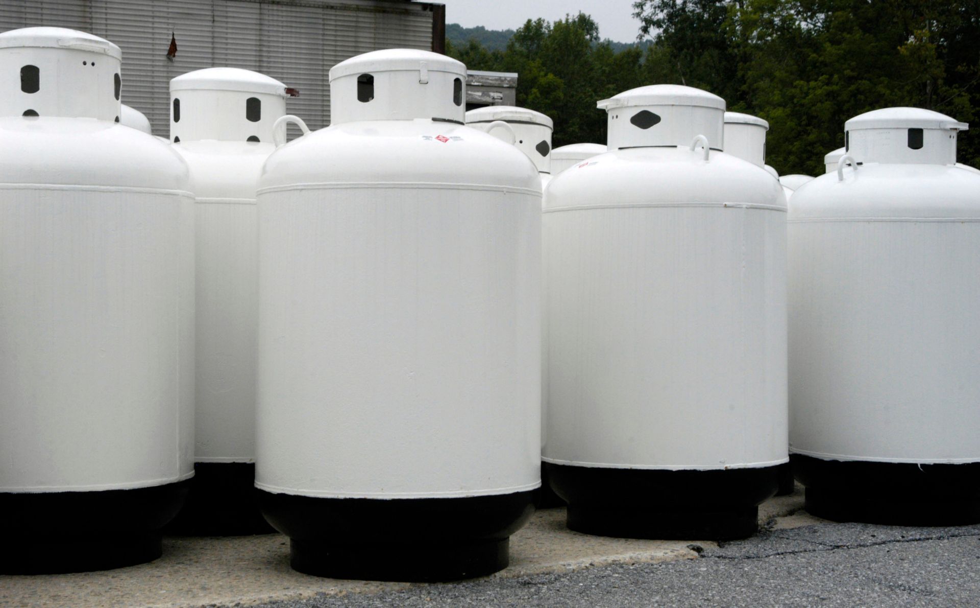 White propane tanks with black bases, outdoors.