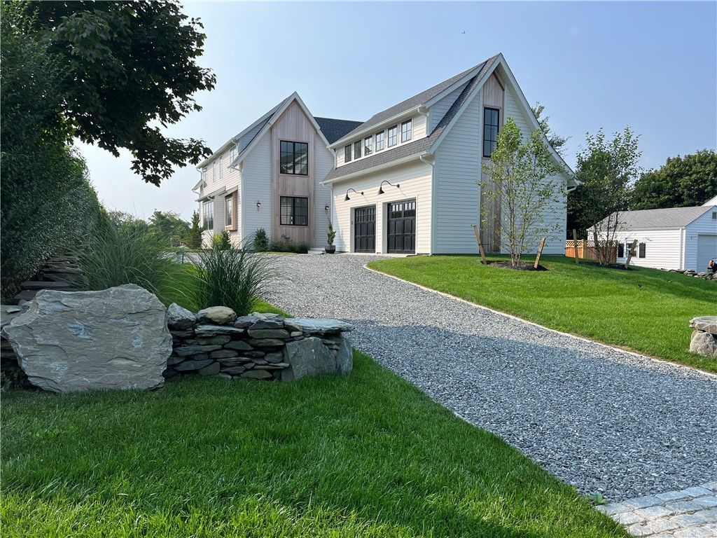 Modern white house with gravel driveway and green lawn.