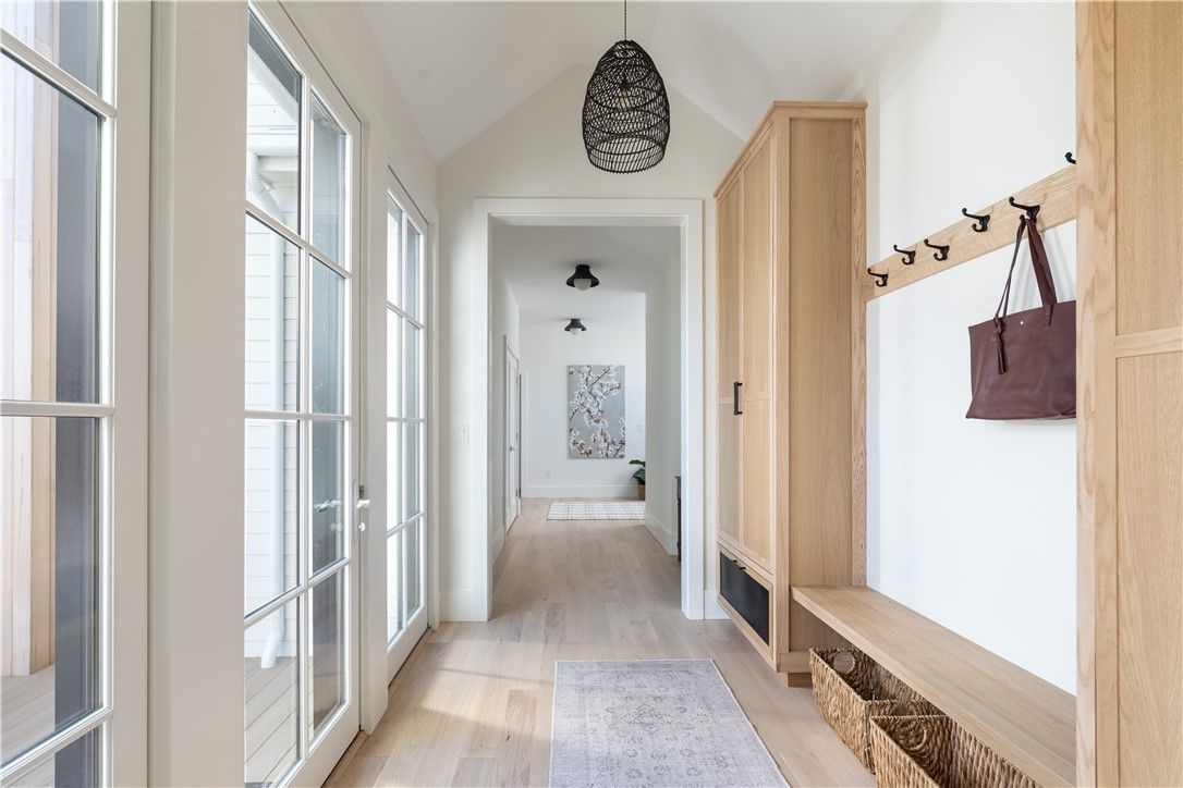 Hallway with light wood floors, built-in storage, and french doors.