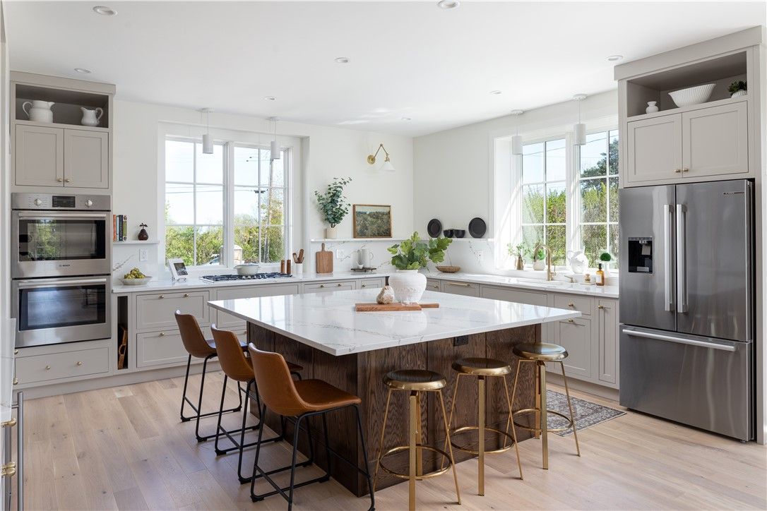 Modern kitchen with a large island, stainless steel appliances, and two windows.