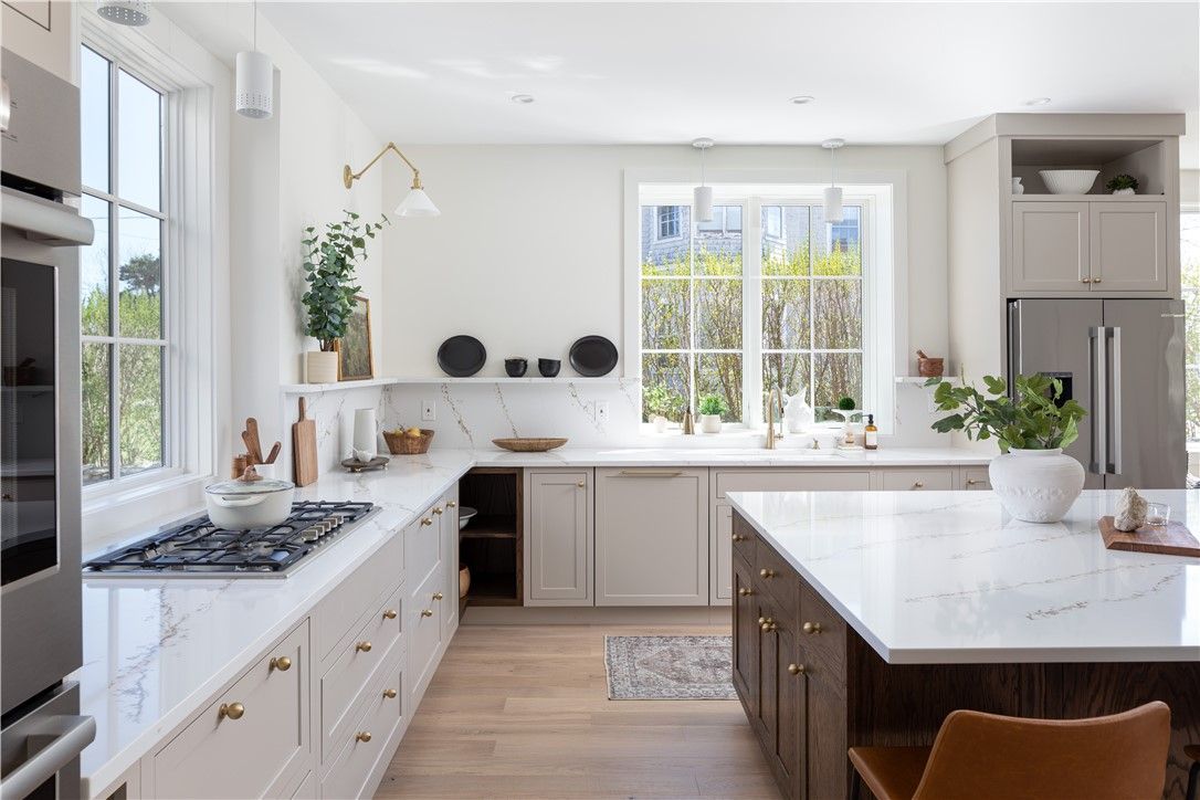 Elegant kitchen with white countertops, light wood floors, and island. Natural light streams in.