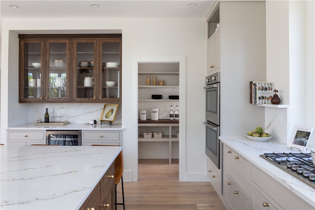 A modern kitchen with a pantry, featuring a white countertop, wooden cabinets, and a double oven.