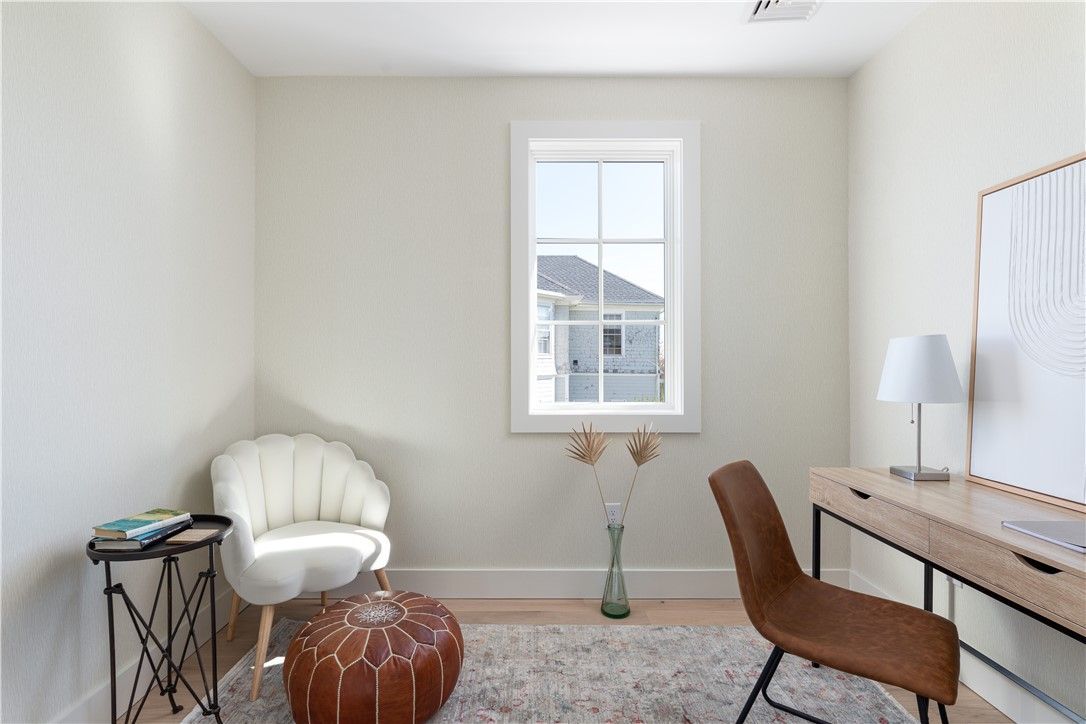A small home office with a desk, chair, window, and decorative elements.