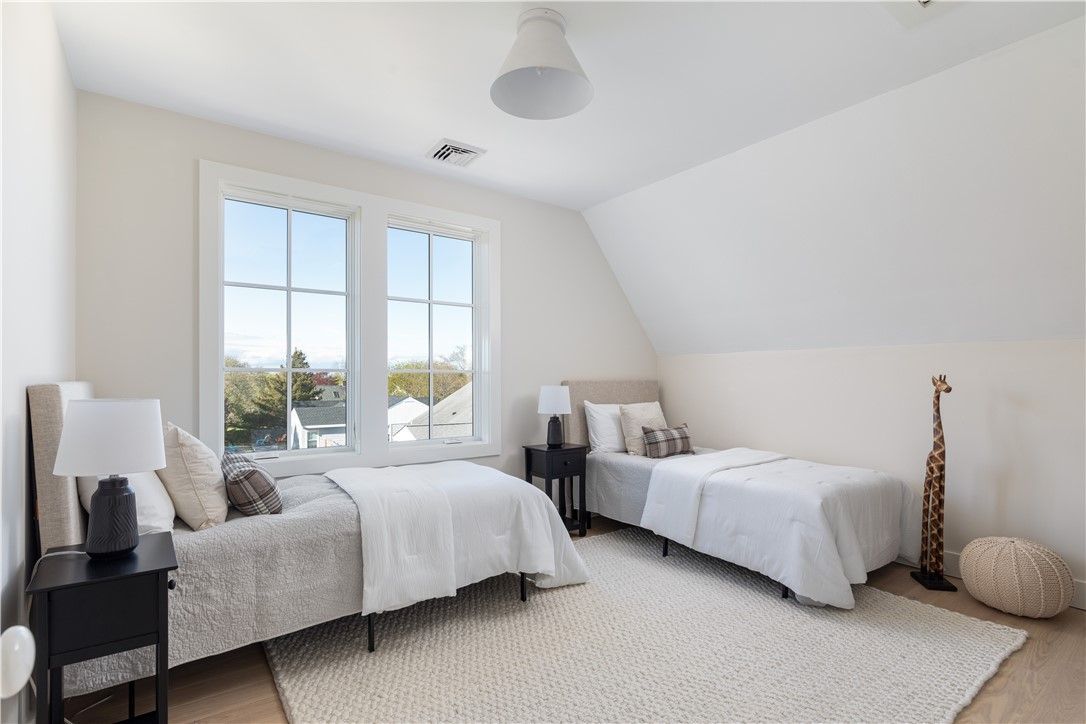 Bedroom with two twin beds, large window, rug, and decorative giraffe statue.