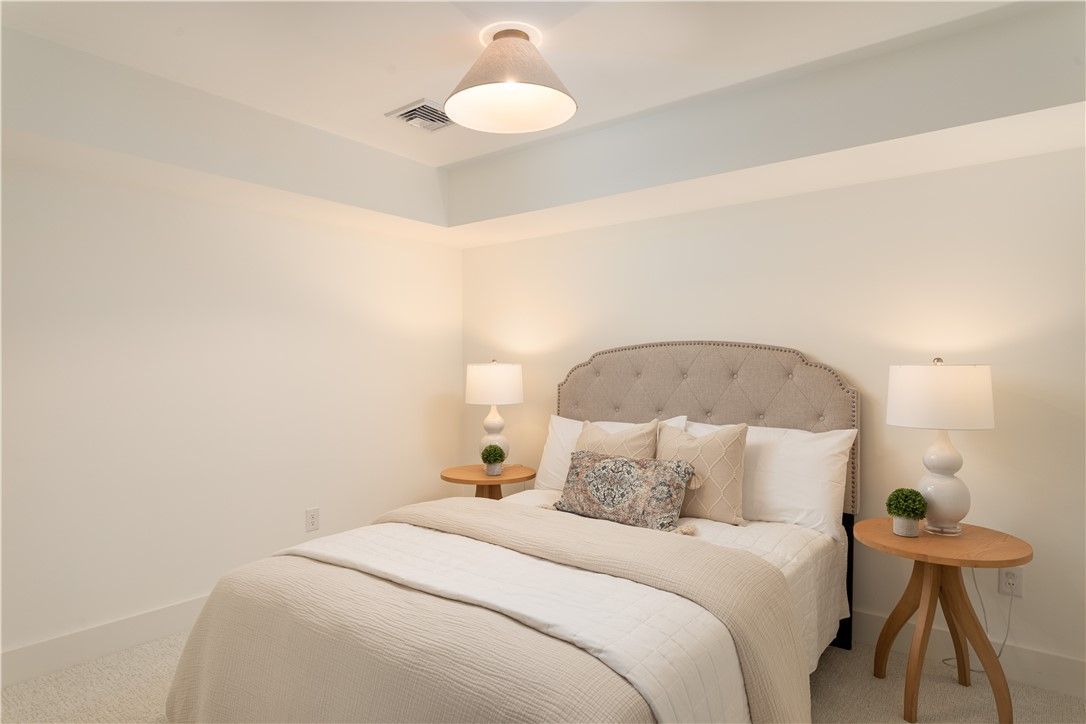 Bedroom with bed, nightstands, lamps, and ceiling light. Neutral tones.