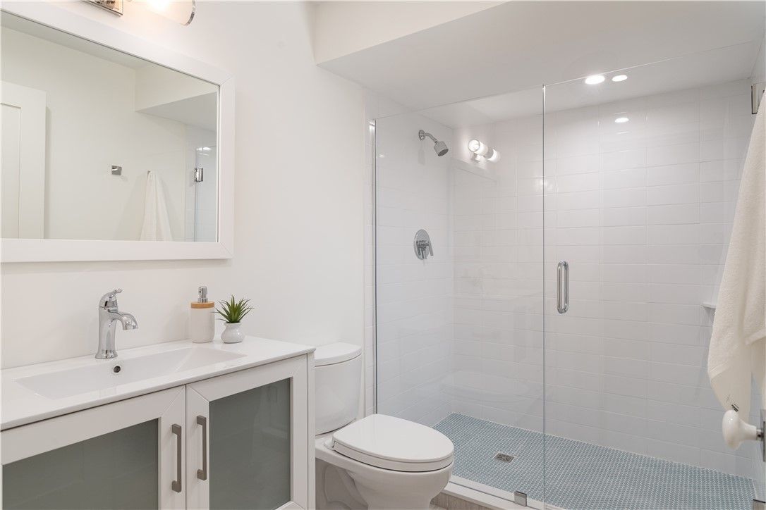 White modern bathroom with a glass shower, toilet, and vanity.