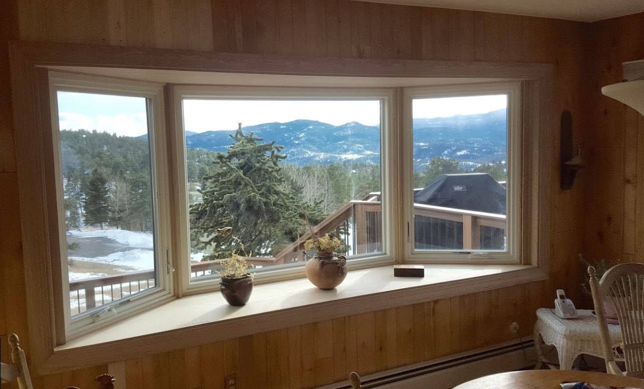 Bay window with wooden trim and paneled wall, overlooking a snowy mountain landscape.