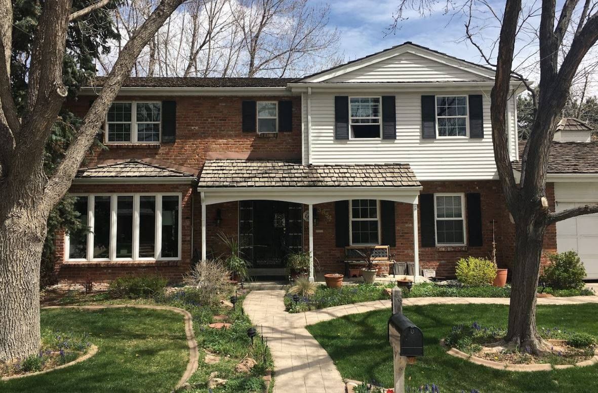 Two-story brick and white house with a walkway leading to the front door.