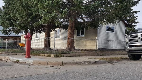 A residential house with a red fire hydrant, a chain-link fence, and a parked truck.
