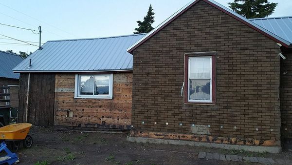 Buildings with dark brown exterior walls and silver metal roofs; one has a window.
