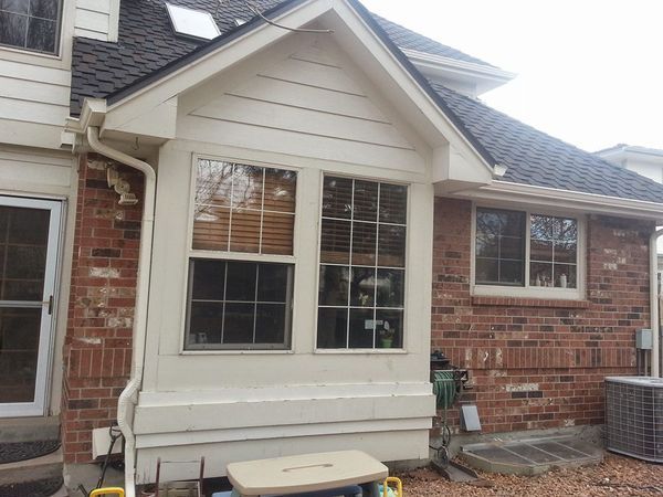 Exterior view of a brick house with a bay window and dark roof.