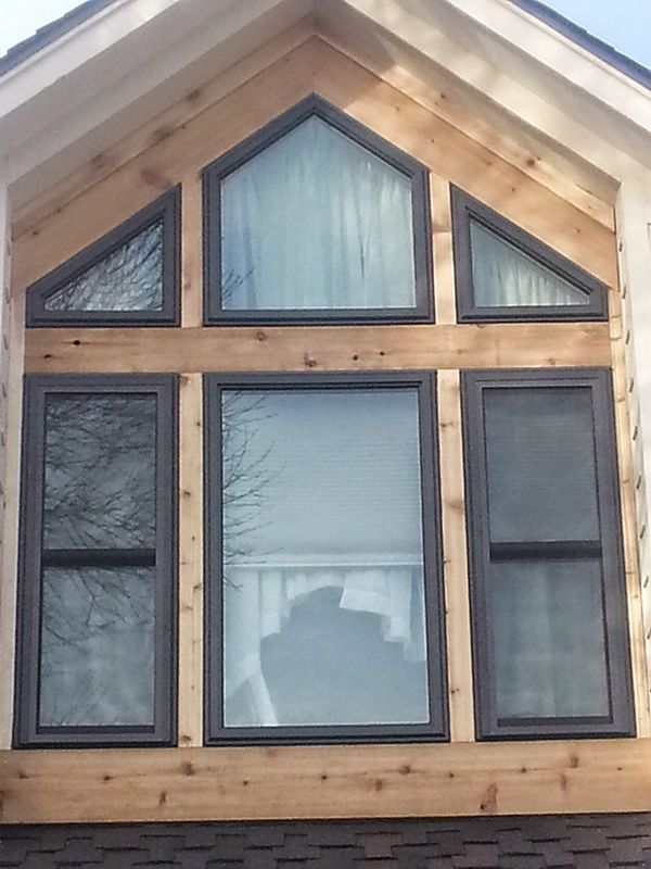 A multi-pane window with dark frames set in natural wood siding.