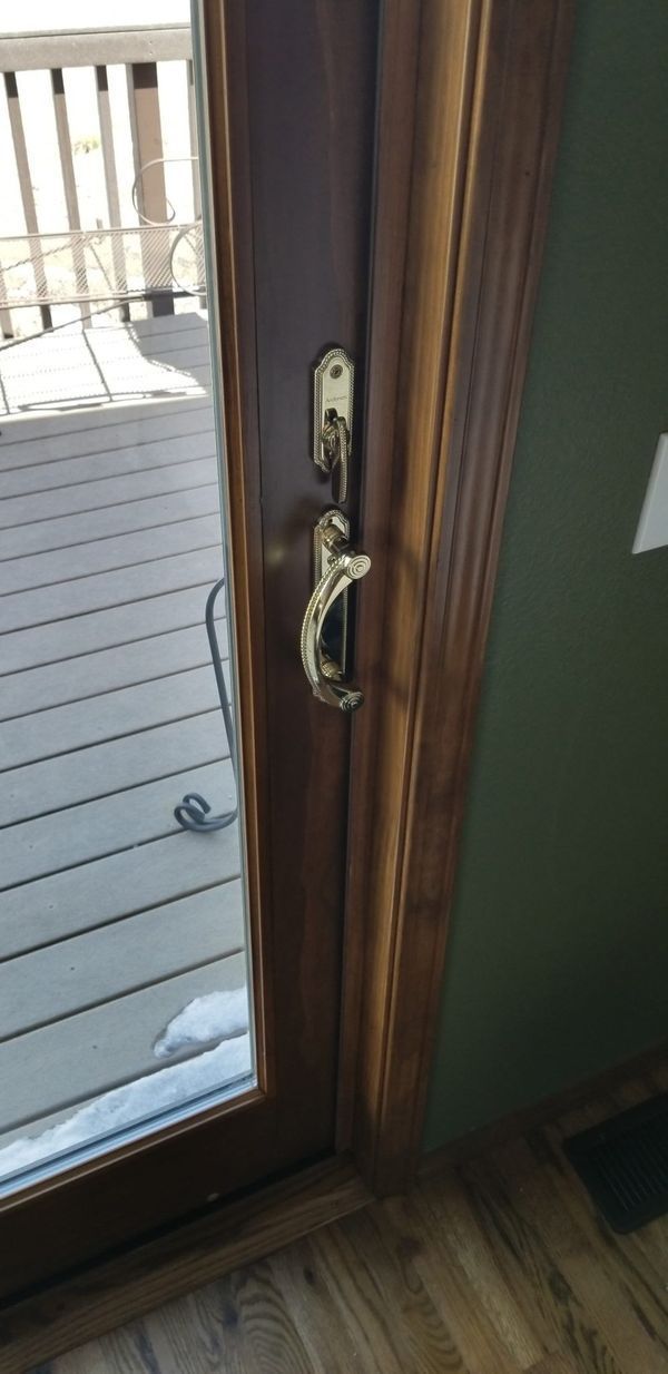 Wooden door with brass handle and lock, leading to a deck with snow.
