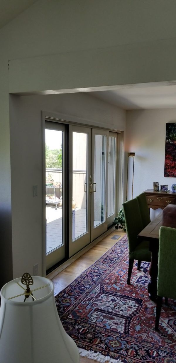 Interior view: sliding glass doors to a patio, dining room with green chairs and a patterned rug.