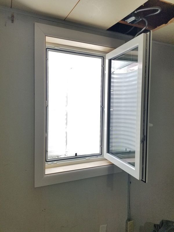 Basement window with white frame, open; showing a window well. Gray walls and ceiling.