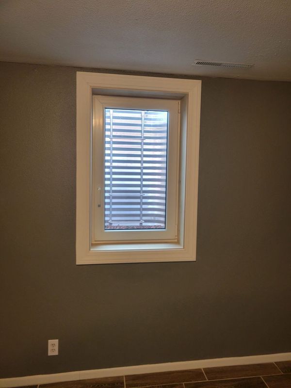 Window with white frame and blinds on gray wall.