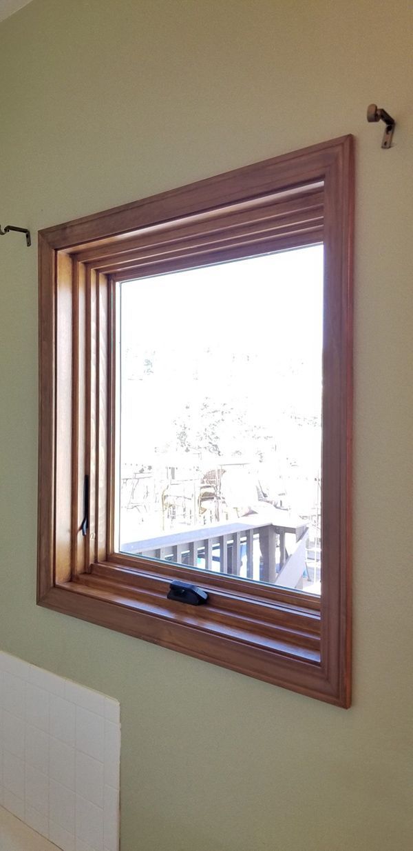 Wooden-framed window in a room with light green walls. The view outside is bright.
