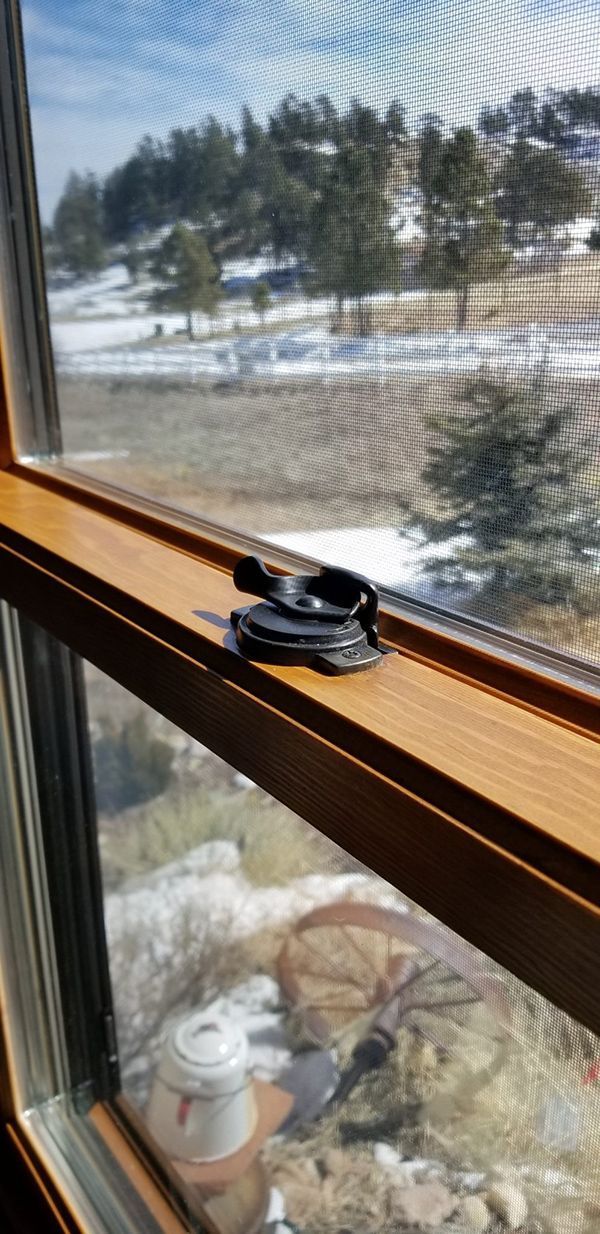 Black camera mount on a wooden windowsill, with a snowy outdoor landscape visible through the window.