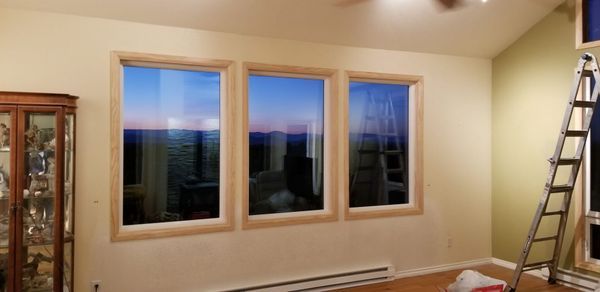 Three windows reflect a colorful sky. An open room with a cabinet and ladder.