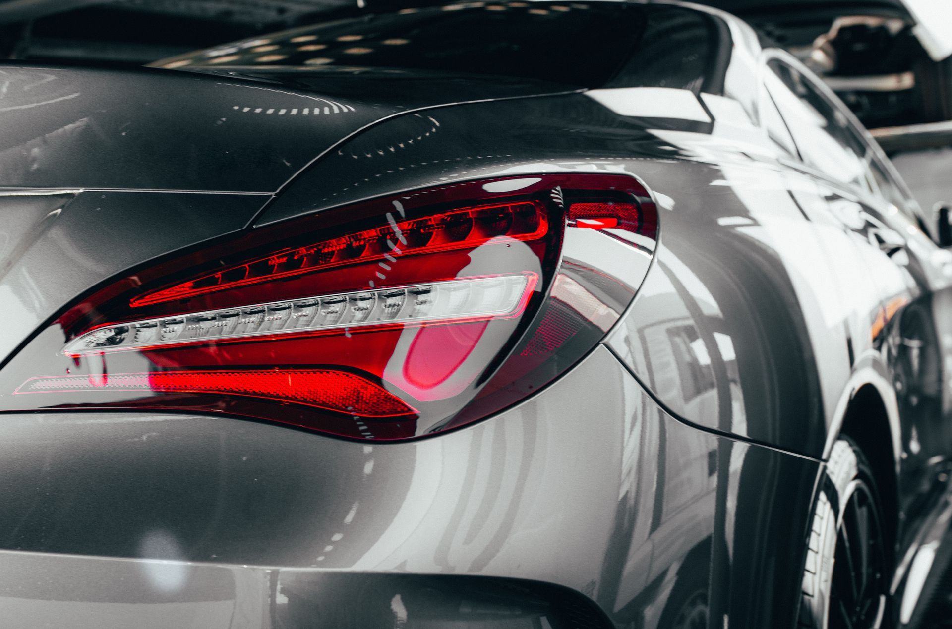 Rear view of a silver car, highlighting its taillight with red and pink details.