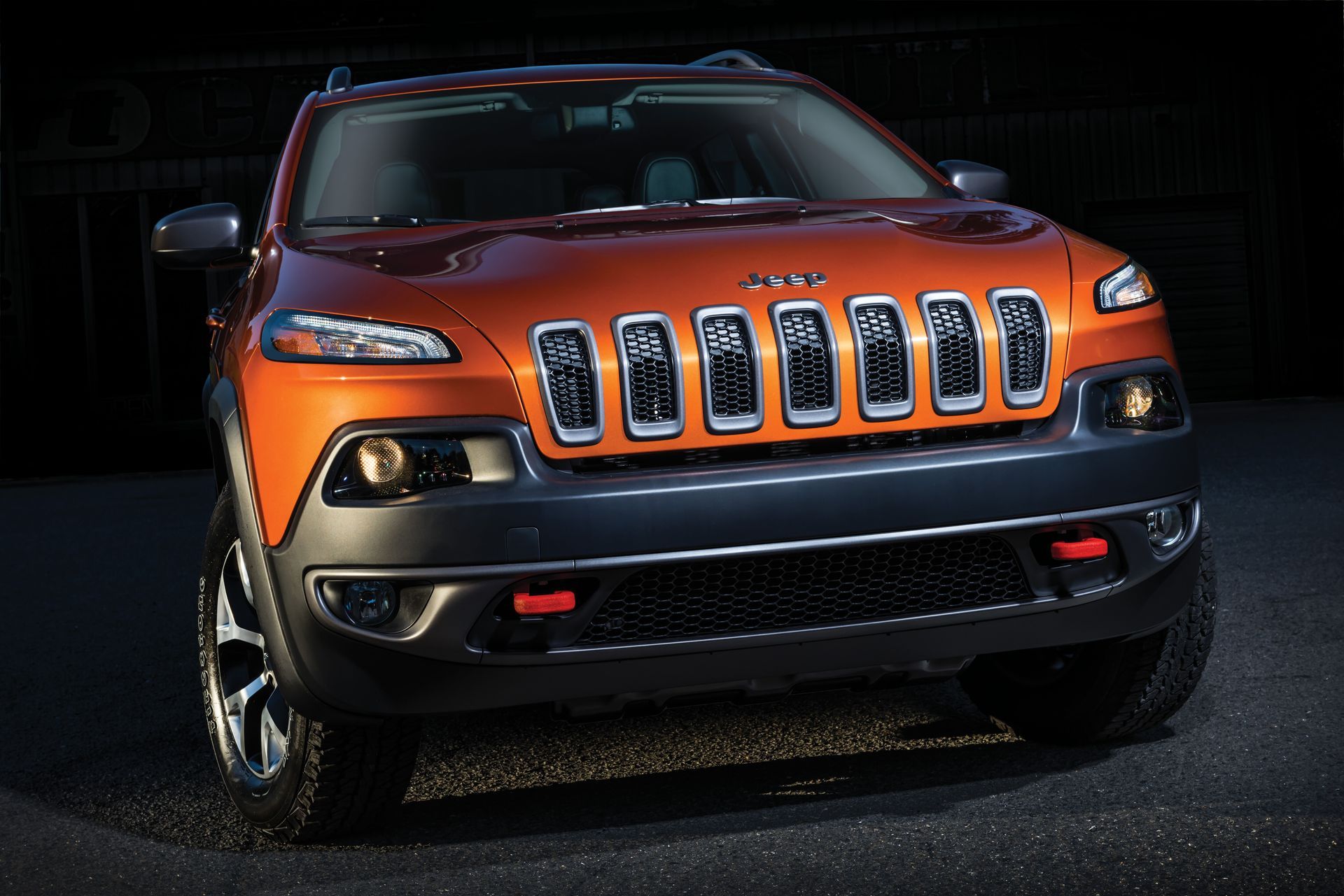 Orange Jeep Cherokee SUV with black accents, front view.