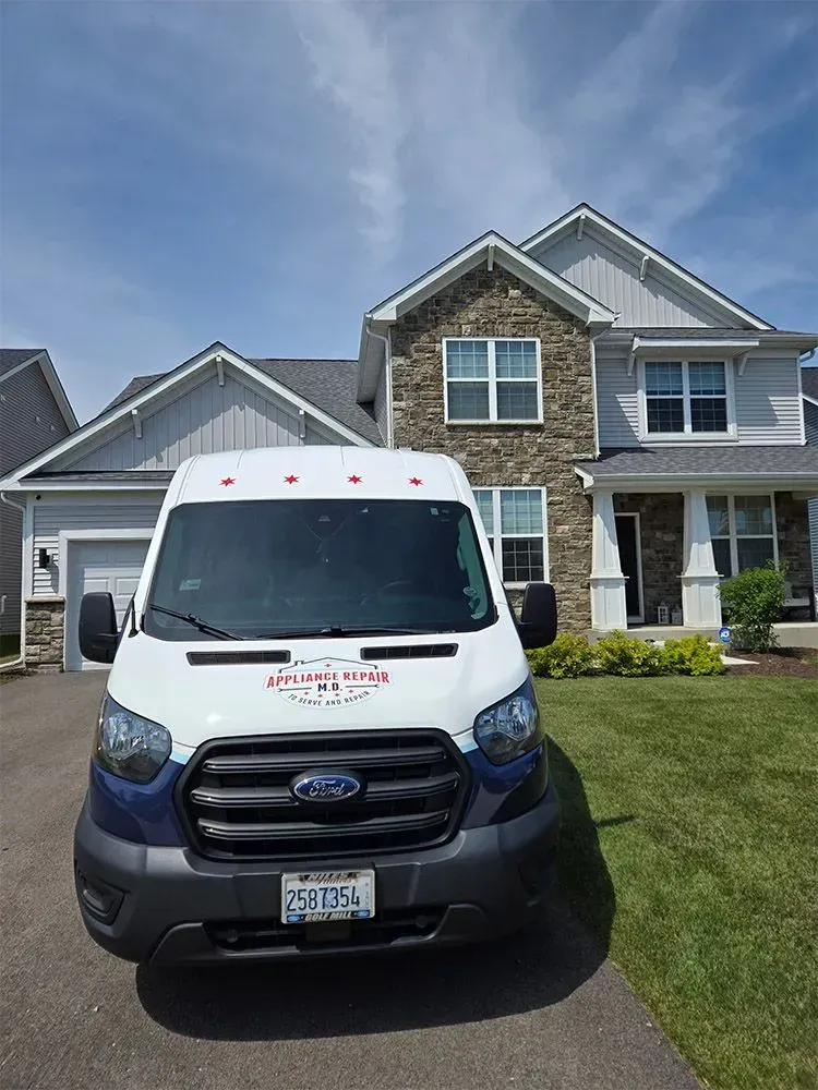 White and blue service van parked in front of a two-story house on a sunny day.