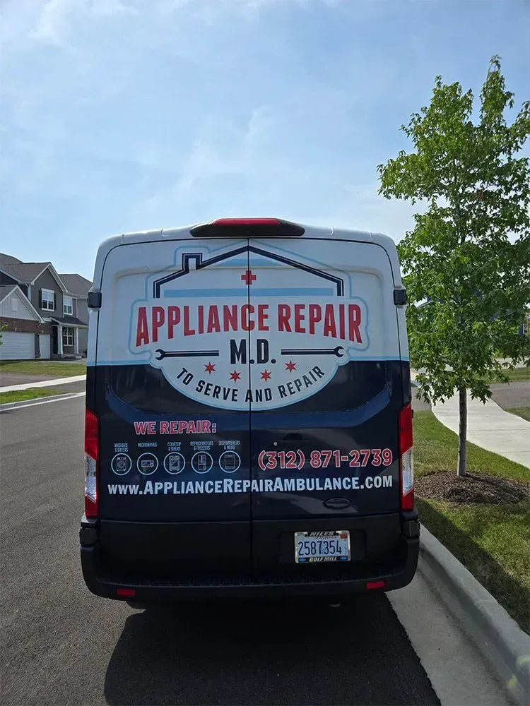 Appliance Repair M.D. van parked on a residential street. White and black with company logo and contact info.