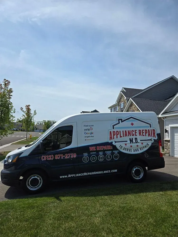 White and blue appliance repair van parked on a lawn in front of a house under a blue sky.