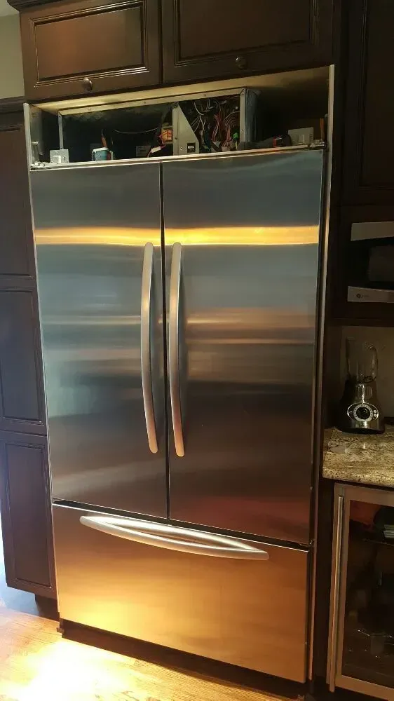 Stainless steel refrigerator built into dark wood cabinetry.