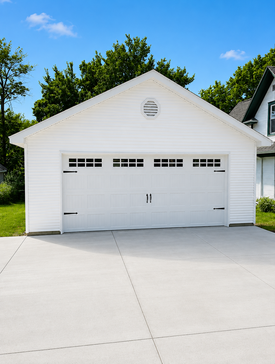 White two-car garage with closed doors and a concrete driveway under a blue sky