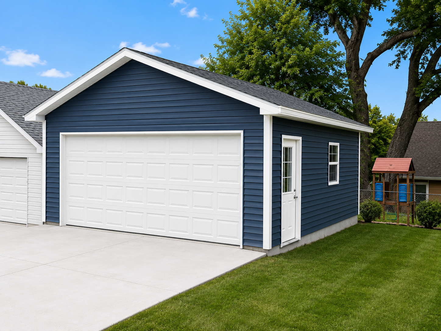 Blue detached garage with white door beside a grassy yard and driveway