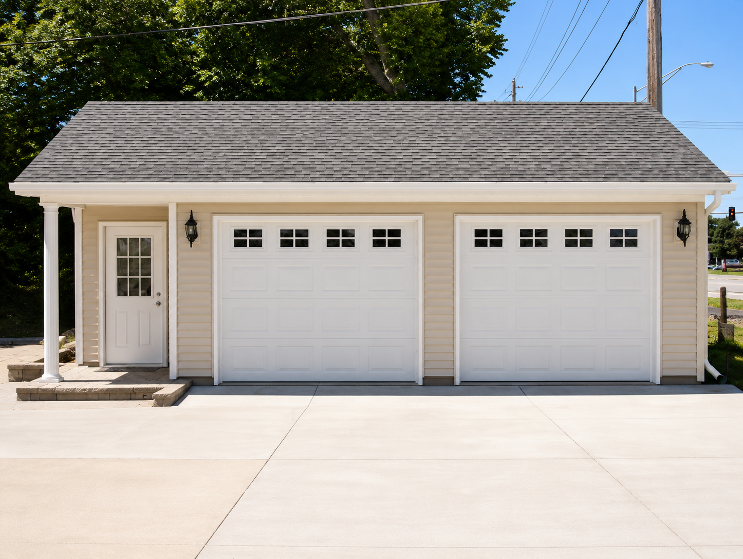Two-car garage with white doors and a side entry, fronted by a wide concrete driveway.