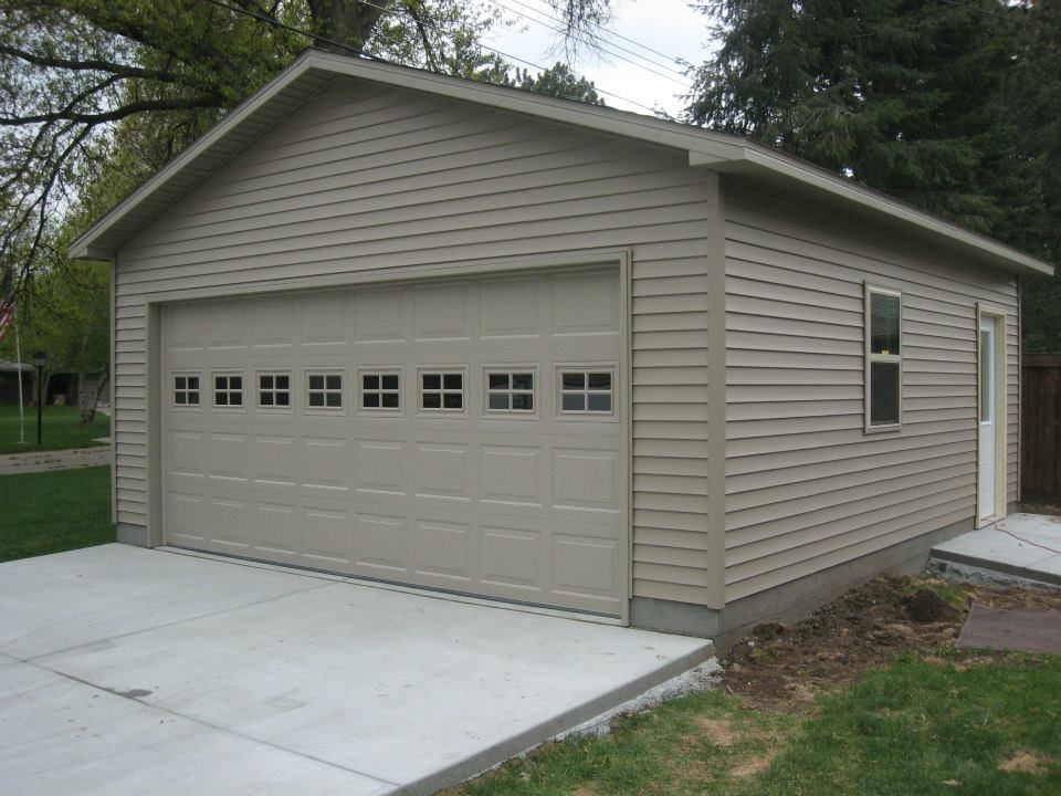 Tan garage with closed door, small window, and concrete driveway.