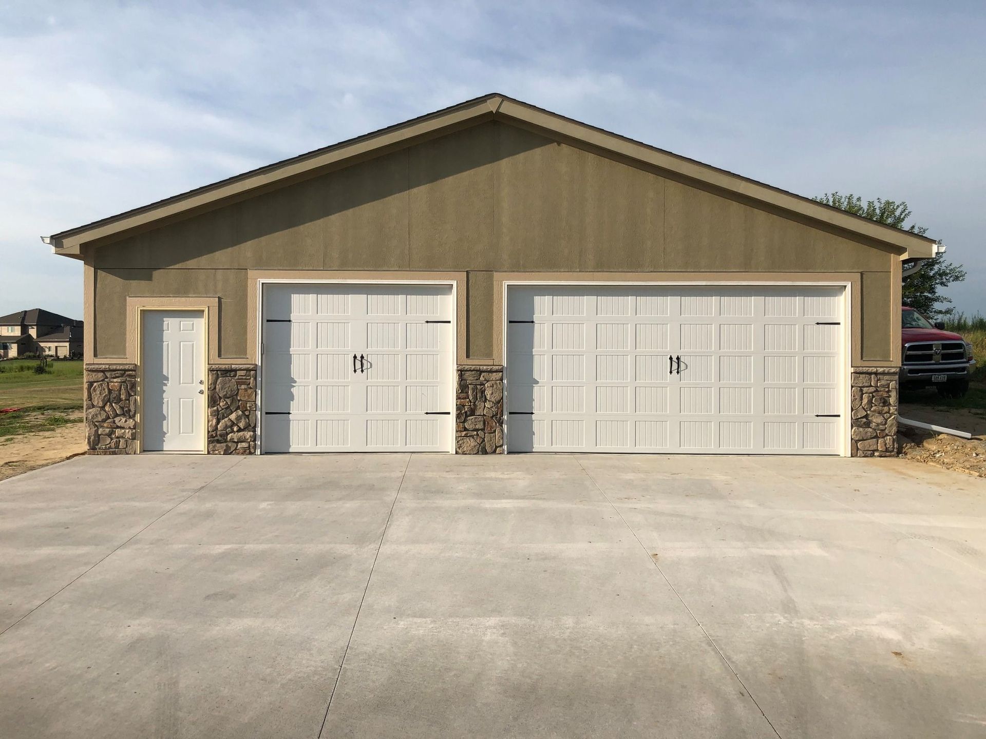 Two-car garage with white doors, tan siding, and a concrete driveway.