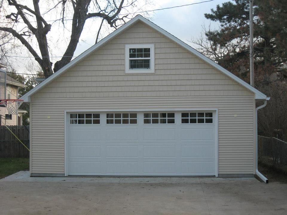 Tan garage with white garage door and small square window.