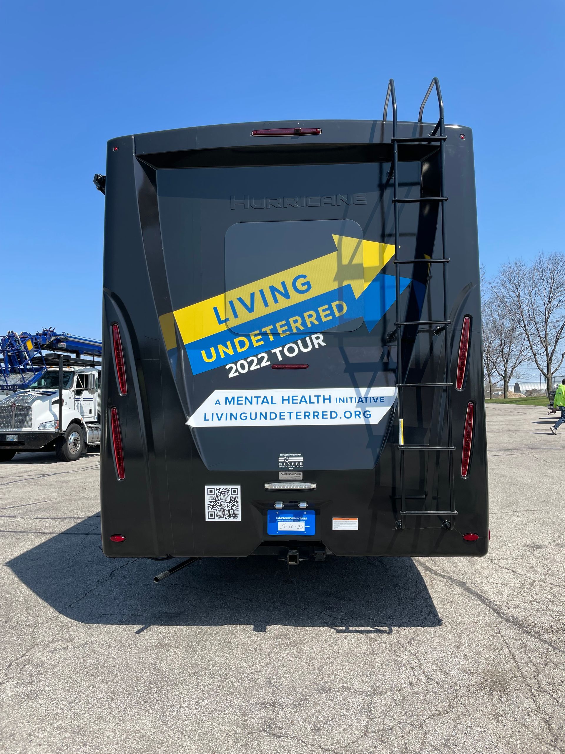 The back of a black rv is parked in a parking lot.