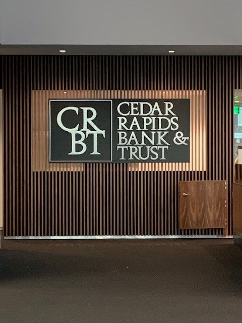 Sign for Cedar Rapids Bank & Trust on a brown vertical striped wall.