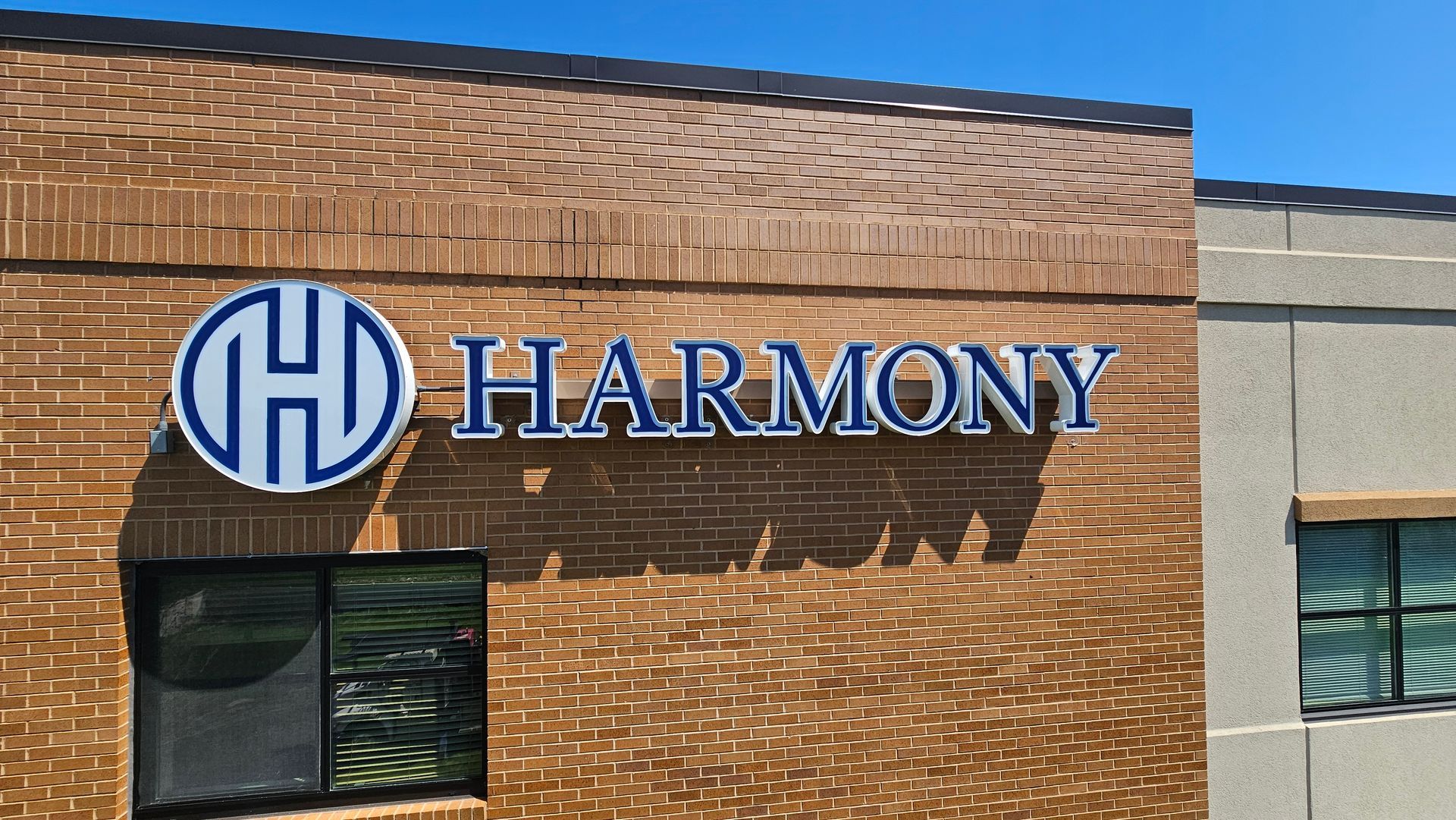 Harmony building sign on a brick wall with a blue logo and text.