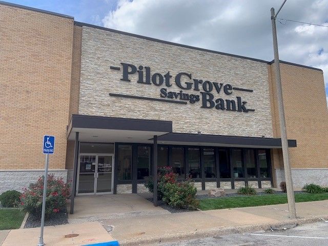 Pilot Grove Savings Bank building with a handicap parking sign and cloudy sky.