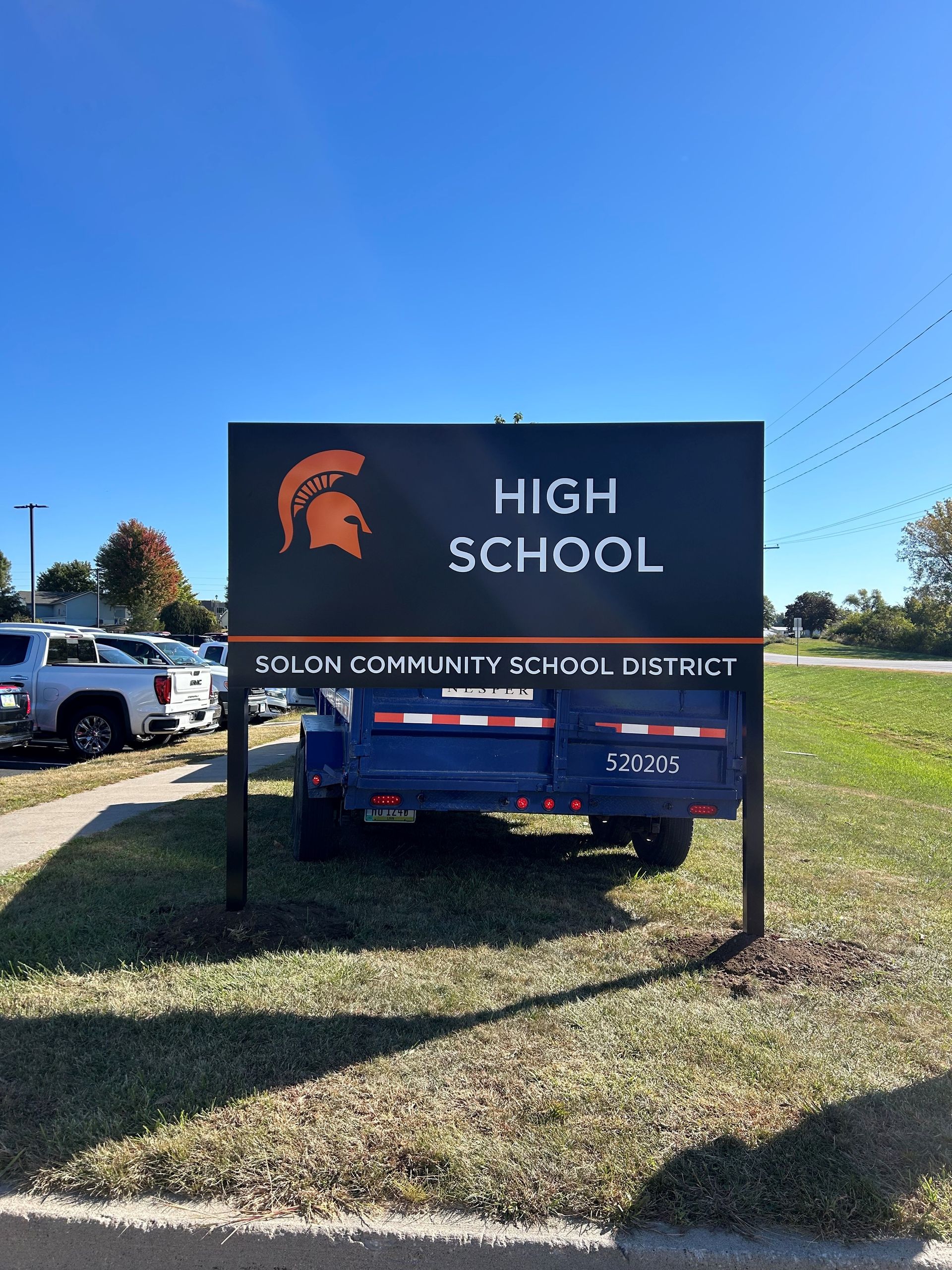 A sign for a high school with a trailer in front of it