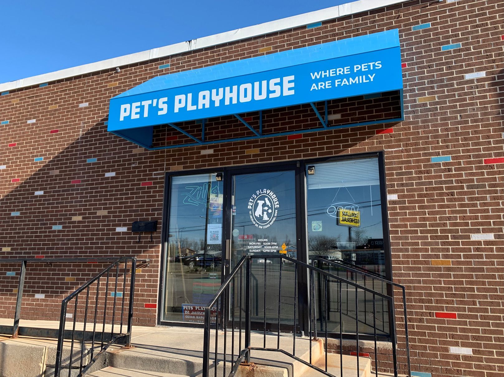 Pet's Playhouse storefront with a blue awning, brick facade, and glass door.